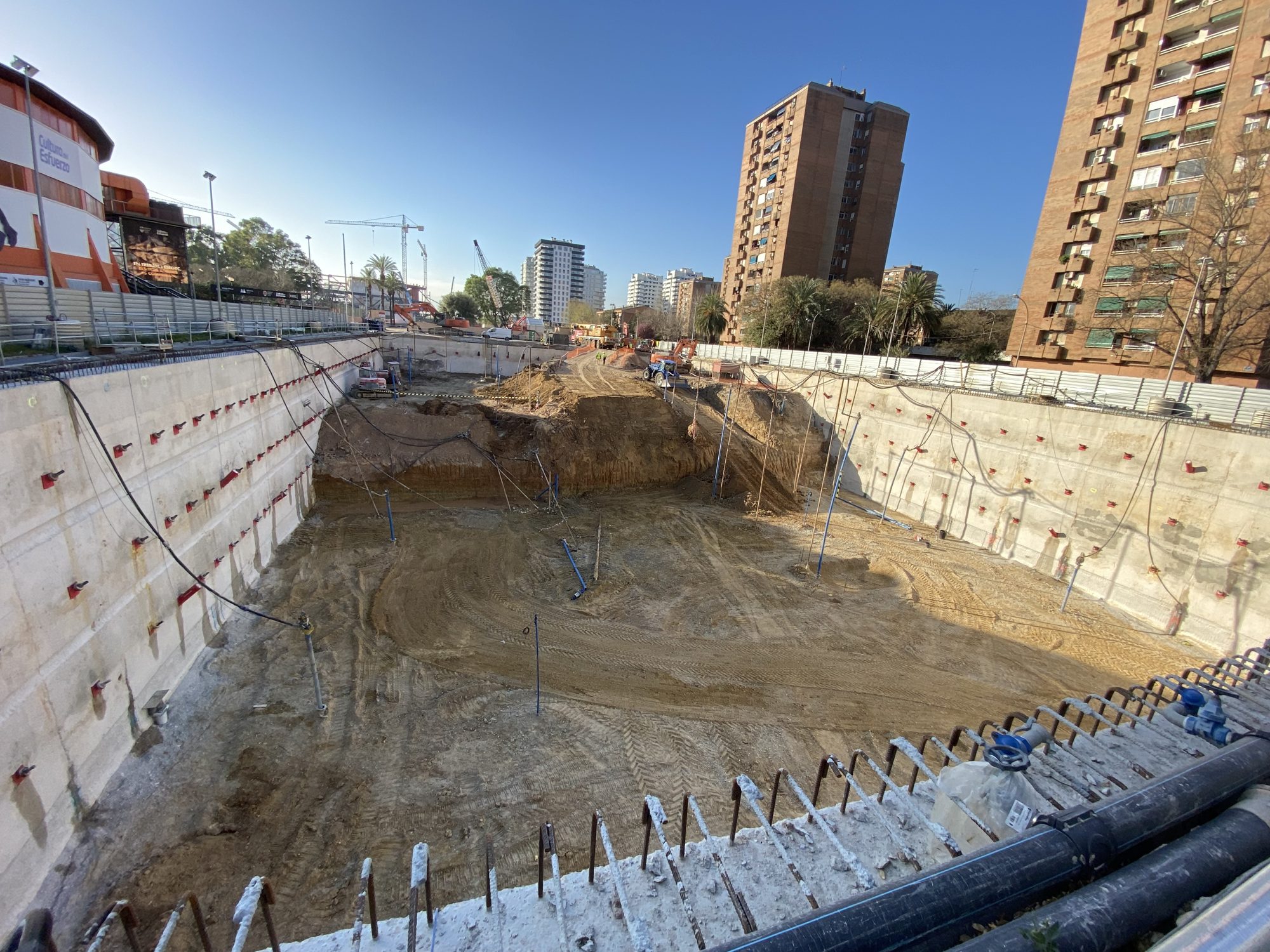 Excavación profunda con muros pantalla anclados en el Parking General del Roig Arena (Valencia), con torres residenciales al fondo.